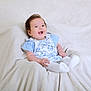 Deyna is registered to the contest to win money with this photo: baby, infant, smiling, happy, blue_clothing, floral_pattern, white_socks, blanket, soft_texture, indoor, portrait, cute, child, sitting, young_child, person, head, face, bright_eyes, comfort