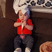 Hope is registered to the contest to win money with this photo: baby, bow, pacifier, couch, blanket, clothing, socks, infant, indoor, child, person, cute, seated, headwear, comfort, soft, pink, red, blue, leopard_print