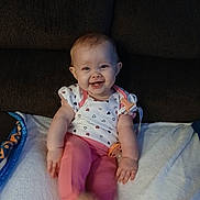 Hope joined the competition — help win amazing prizes! baby, child, smiling, cute, infant, couch, blanket, clothing, person, happy, indoor, face, sitting, pink_pants, white_shirt, heart_pattern, pacifier, home, young_child, cozy