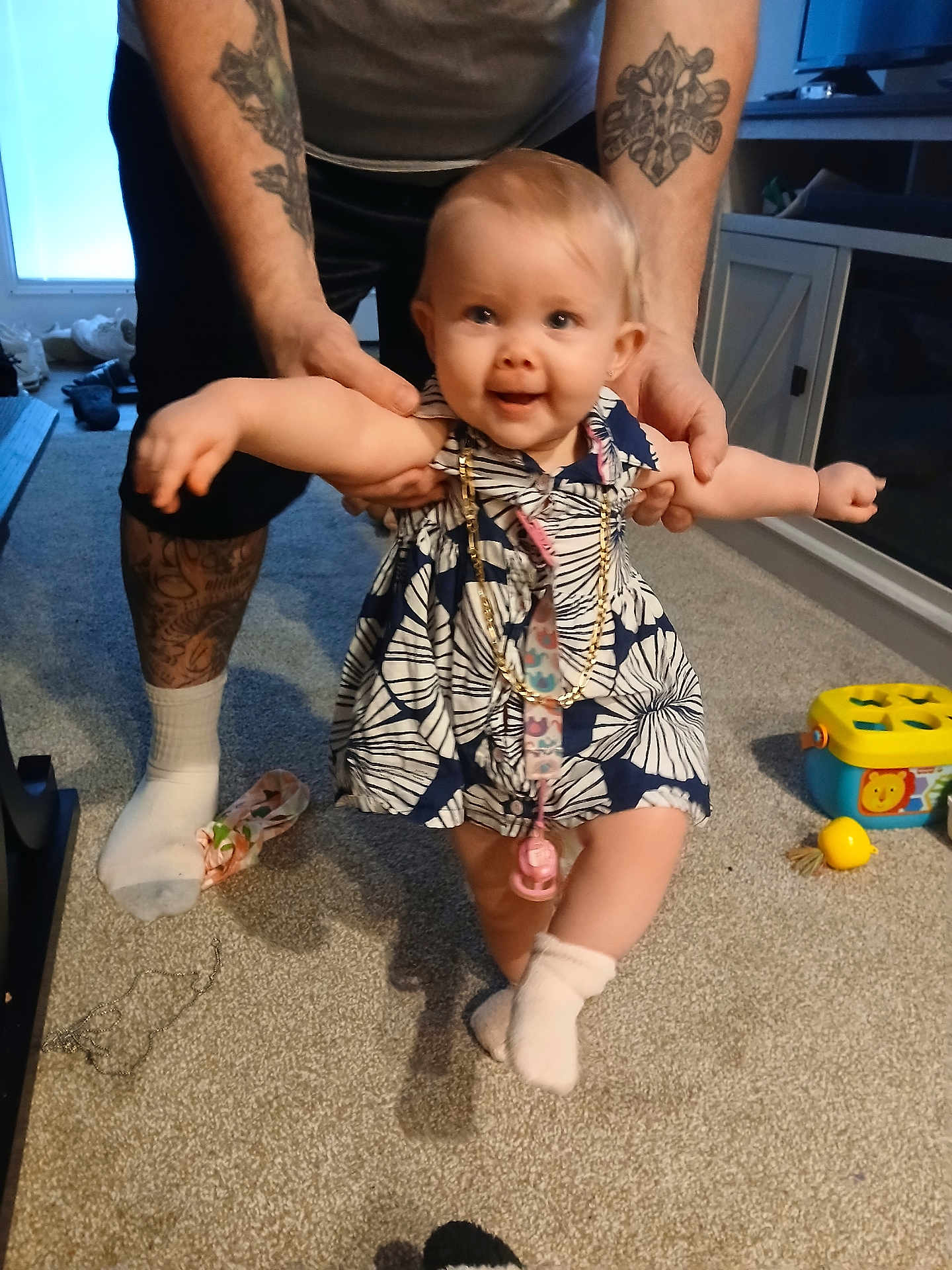 Hope joined the competition — help win amazing prizes! baby, child, toddler, dress, carpet, adult, tattoos, toy, pacifier, chain, indoor, smiling, person, holding, footwear, sock, furniture, cabinet, floor, playtime