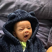 Adam joined the competition — help win amazing prizes! baby, hoodie, black_clothing, yawning, infant, cute, face, child, soft_texture, ears, bed, blanket, sleepy, toddler, portrait, expression, warm_clothing, cozy, person, indoor