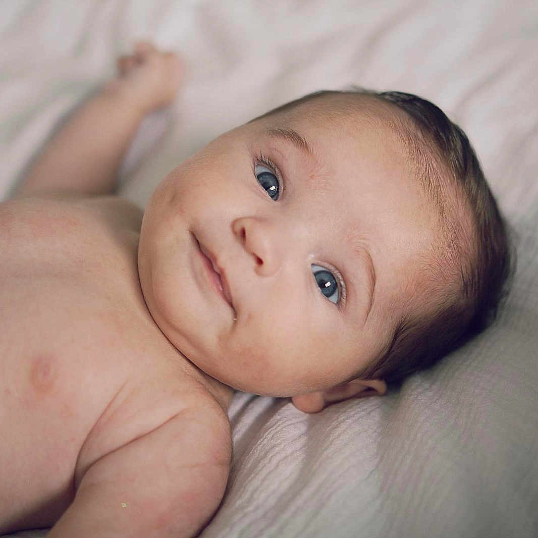 Gaby participe au concours pour gagner de l'argent avec cette photo : baby, blanket, blue_eyes, child, closeup, cute, expression, face, head, human, indoors, infant, lying_down, newborn, peaceful, portrait, skin, smile, soft_lighting, young