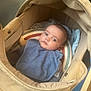 baby, stroller, blue_bib, blanket, rainbow_cushion, infant, face, eyes, clothing, comfort, indoor, soft_light, cute, child, portrait, resting, young, people, head, cozy