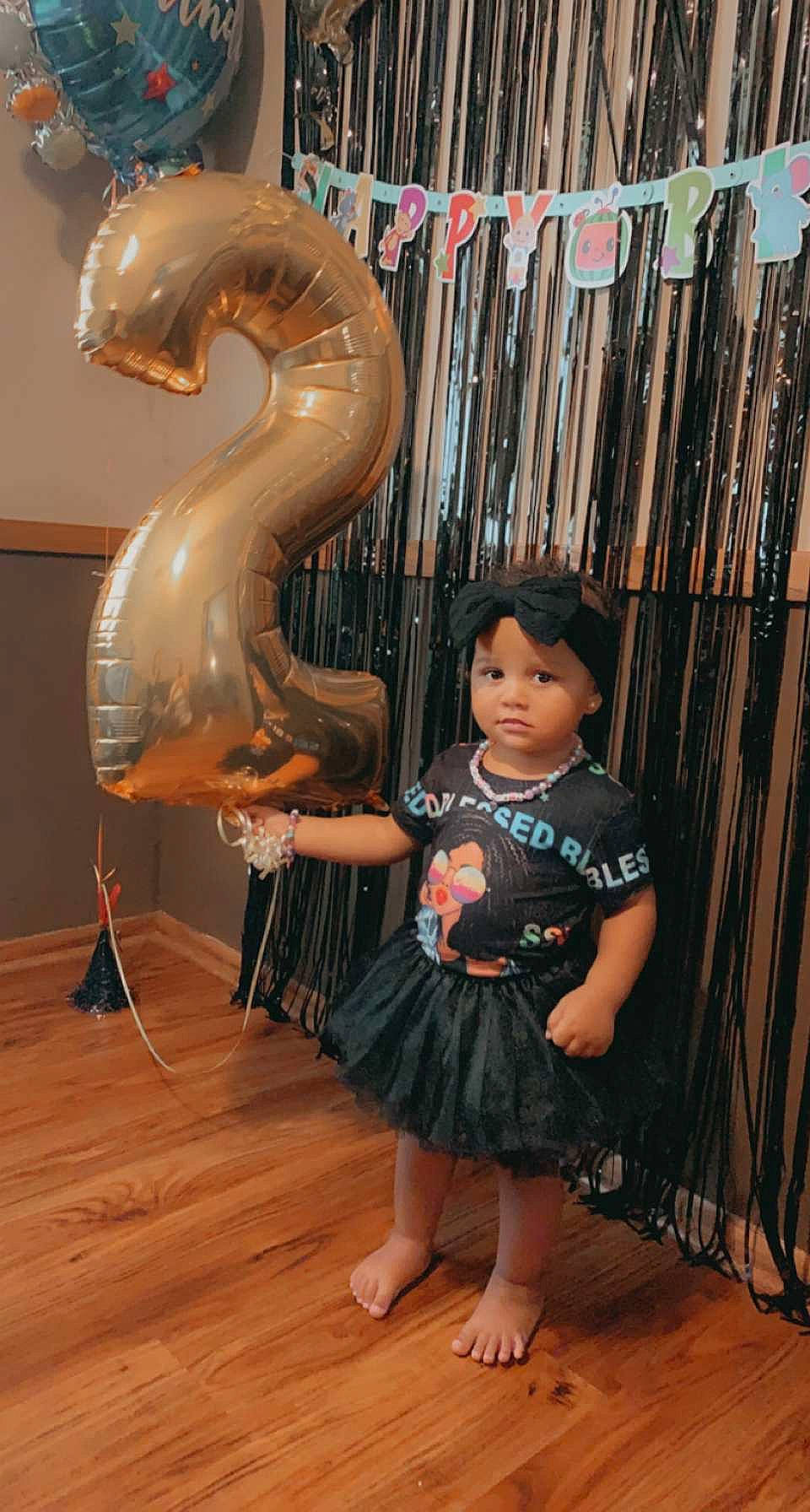 Kennedy is registered to the contest to win money with this photo: art, child, fence, flooring, foot, fun, hair, hardwood, head, headwear, human_body, laminate_flooring, leisure, person, sandal, sitting, t_shirt, toddler, visual_arts, wood