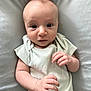 baby, infant, face, hands, onesie, cushion, soft, curious, expression, skin, small_hands, lying_down, indoors, portrait, child, cute, wide_eyes, pale_clothing, human, newborn