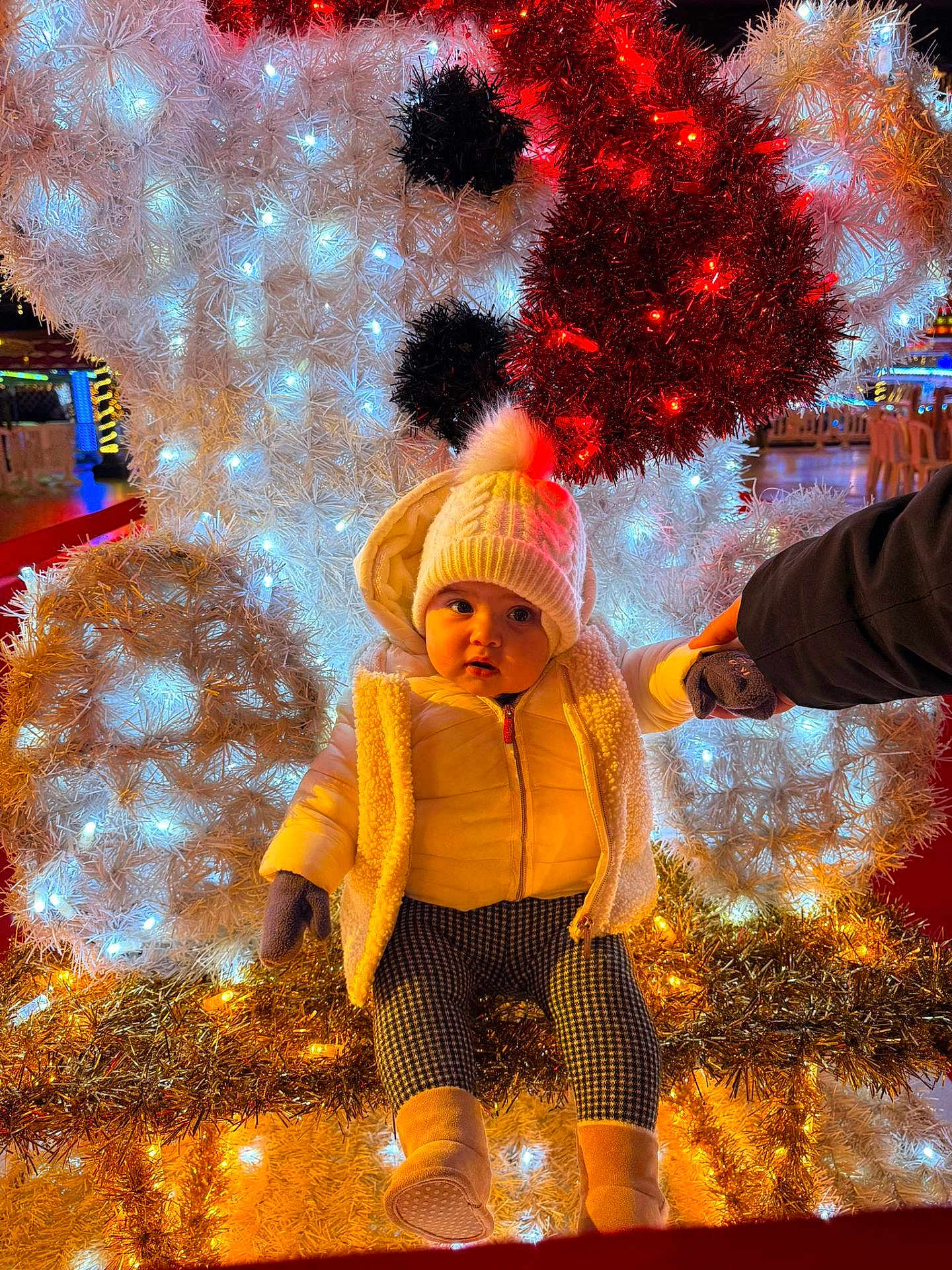 Melya participe au concours pour gagner de l'argent avec cette photo : baby, child, winter_clothing, hat, gloves, boots, holiday_lights, decorations, festive, illumination, toy_bear, white, red, night, outdoor, person, holding_hand, warm_clothing, cute, seasonal