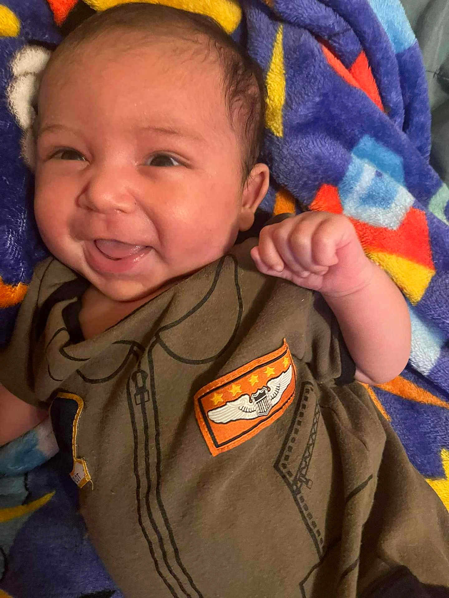 Kymani joined the competition — help win amazing prizes! baby, smiling, infant, clothing, blanket, fist, happy, face, person, cute, portrait, child, lying_down, colorful, soft, young, indoors, apparel, expression, infancy