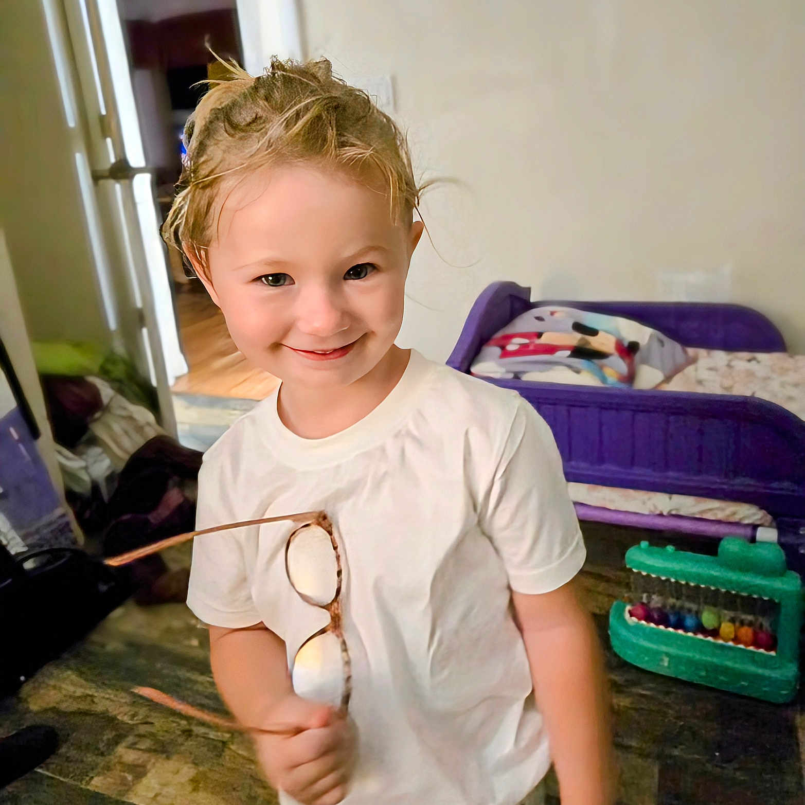Bella joined the competition — help win amazing prizes! bed, casual_clothing, child, childhood, floor, furniture, glasses, hair, happy, home, indoor, person, playing, portrait, room, smiling, toy, white_tshirt, young, young_child