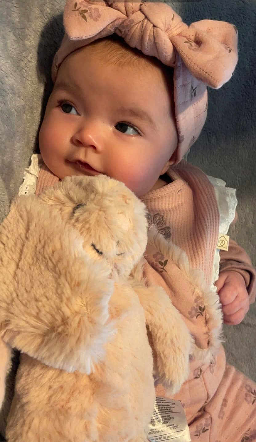 Kinsley joined the competition — help win amazing prizes! baby, infant, headband, bow, stuffed_animal, plush_toy, pink_clothing, floral_pattern, soft_texture, cute, portrait, child, toddler, indoor, cozy, closeup, face, hand, blanket, sleepy