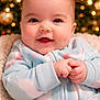 Kinsley joined the competition — help win amazing prizes! baby, smiling, infant, onesie, cozy, hands, face, christmas_tree, holiday, festive, blurred_background, indoor, cute, child, portrait, warm_lighting, happy, soft_texture, seated, newborn