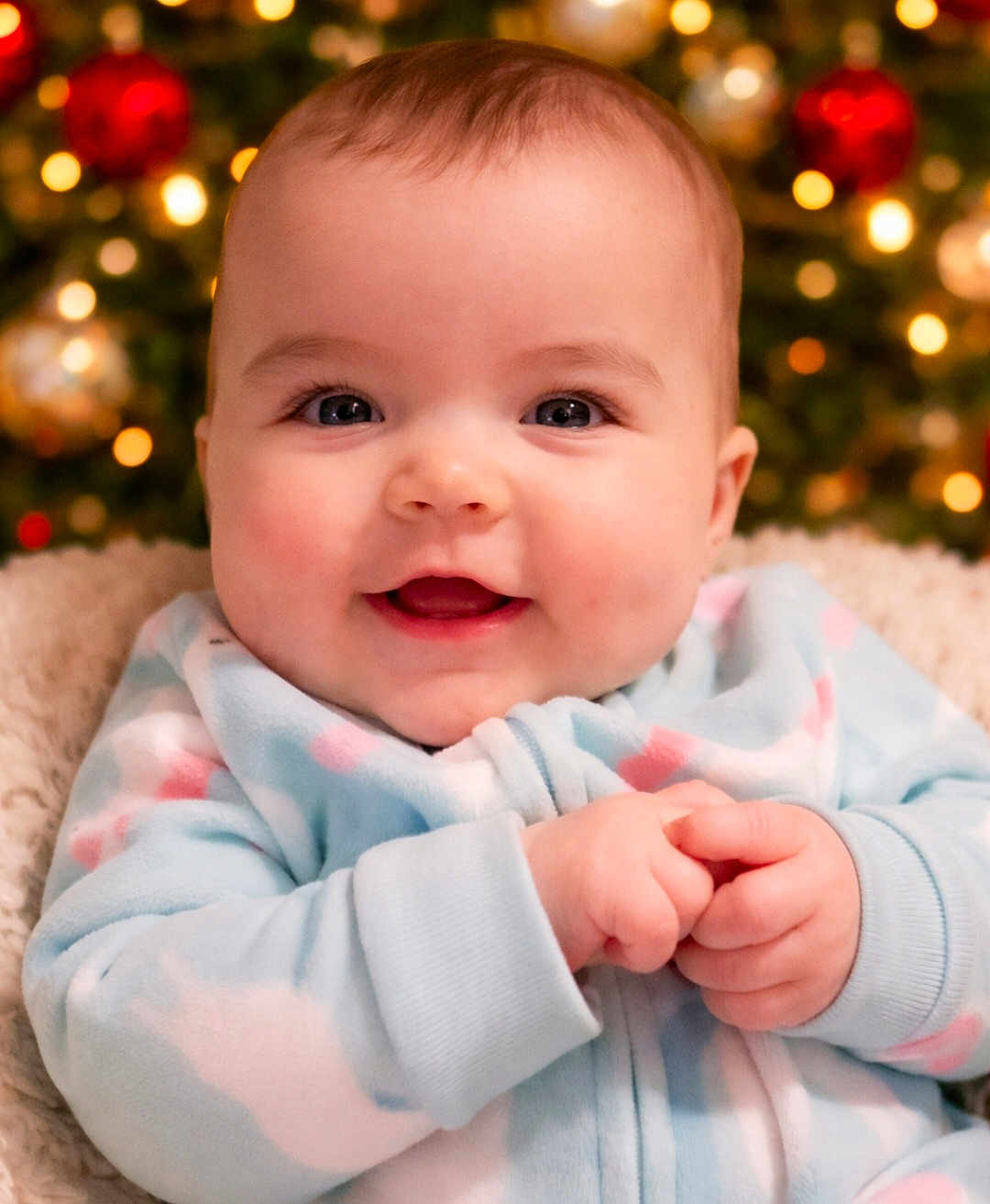 Kinsley joined the competition — help win amazing prizes! baby, infant, smiling, face, hands, onesie, cozy, pastel_colors, christmas_tree, holiday, bokeh, indoor, cute, child, portrait, happy, soft_lighting, warm_colors, closeup, festive