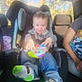 Landyn Scott is registered to the contest to win money with this photo: toddler, child, car_seat, toy, controller, socks, green, jeans, smiling, person, car_interior, seatbelt, sunlight, window, adult_arm, casual_clothing, seat, daylight, happy, playful
