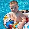 child, toddler, pool, water, inflatable_ring, donald_duck, smiling, summer, outdoor, swimming, fun, cute, happy, floating, blue, skin, boy, recreation, vacation, sunlight
