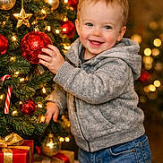 Landyn Scott joined the competition — help win amazing prizes! toddler, child, smiling, christmas_tree, ornament, red_ball, gold_star, candy_cane, holiday_lights, gift_box, wrapped_presents, cozy_clothing, hoodie, jeans, indoor, festive, holiday, celebration, happy, portrait