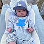 baby, infant, child, pajamas, hat, blue_star, baby_seat, toy, plush_toy, gray_clothing, white_socks, face, person, indoor, cushion, straps, cute, small_hands, expression, seated