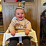 Rowan joined the competition — help win amazing prizes! baby, child, high_chair, crown, smiling, sweater, bear_design, indoor, wood_paneling, happy, cute, celebration, infant, clothing, person, face, sitting, pants, rosy_cheeks, decor
