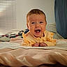 Alaina is registered to the contest to win money with this photo: baby, bed, blanket, child, cozy, cute, expression, face, happy, home, indoors, infant, lying_down, newborn, person, portrait, smiling, soft_lighting, warm_colors, yellow_clothing