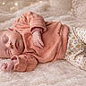 Hélyna participe au concours pour gagner de l'argent avec cette photo : baby, newborn, sleeping, infant, blanket, cozy, clothing, sweater, pants, floral_pattern, soft_lighting, indoors, peaceful, cute, child, portrait, resting, fairy_lights, warm_colors, comfort