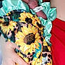 newborn, baby, blanket, sunflower_pattern, mint_green, hand, fingers, sleeping, person, red_clothing, cradle, closeup, indoor, soft_light, peaceful, infant, wrapped, fabric, skin, portrait