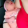Rayleigh is registered to the contest to win money with this photo: baby, newborn, infant, person, arm, hand, tattoo, heart_tattoo, clothing, pink_hat, peach_outfit, red_top, sleepy, holding, indoor, furniture, hospital_band, skin, closeup, tender_moment