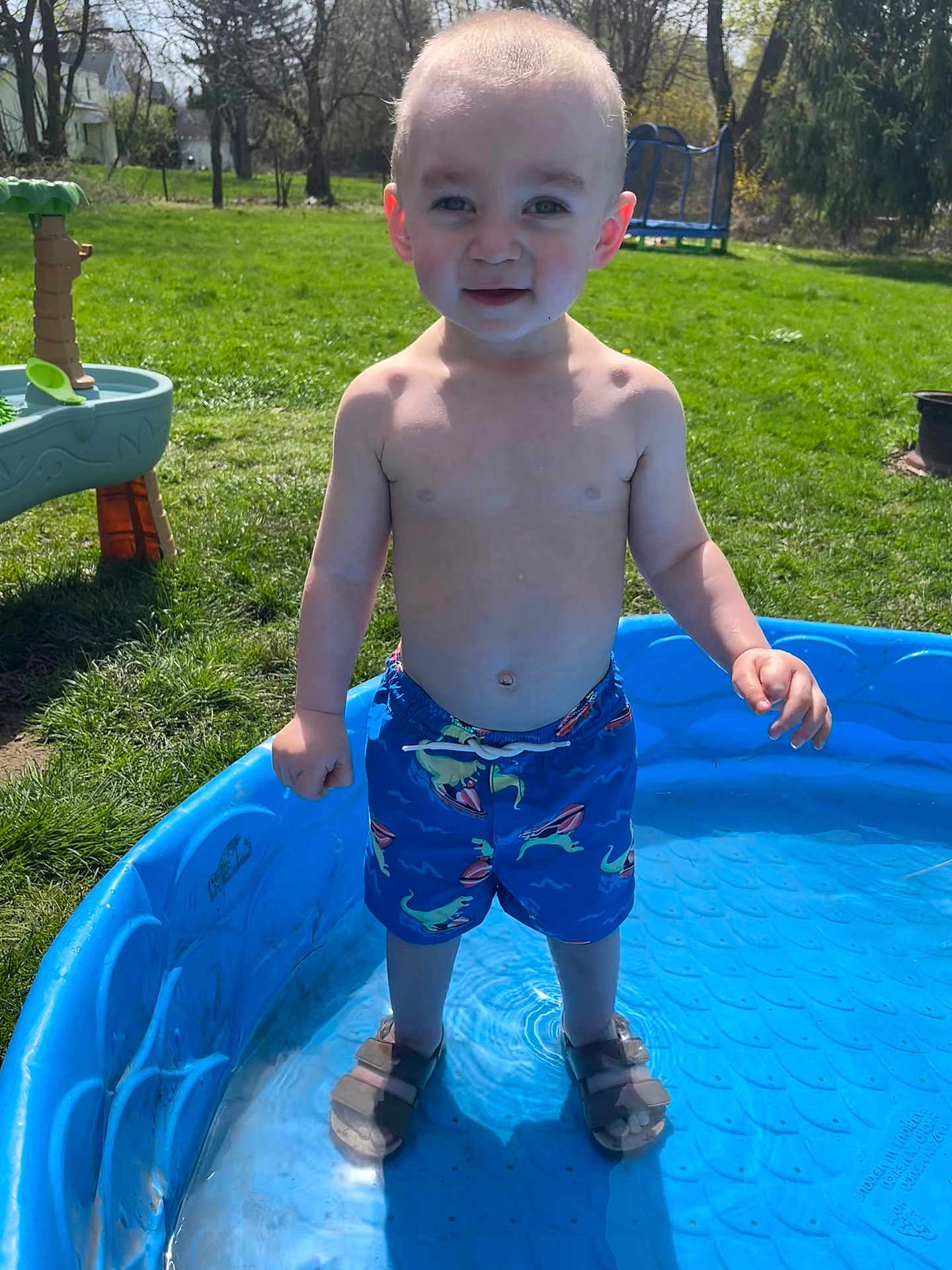 Levi joined the competition — help win amazing prizes! child, toddler, pool, water, swim_trunks, sandals, outdoor, grass, sunlight, backyard, play, summer, toy, happy, bare_chested, blue, nature, trees, recreation, fun