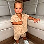 Taysem participe au concours pour gagner de l'argent avec cette photo : toddler, child, indoor, standing, beige_clothing, shorts, shirt, white_sneakers, leather_couch, wood_floor, curly_hair, blush, looking_at_camera, furniture, modern_interior, skin, person, footwear, casual_clothing, cute