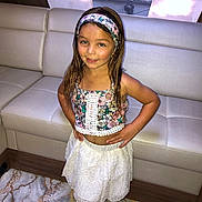 Djiwai participe au concours pour gagner de l'argent avec cette photo : child, girl, standing, smiling, indoors, floral_clothing, white_skirt, headband, wet_hair, carpet, couch, curtains, hand_on_hip, pose, portrait, young, fashion, casual, happy, home