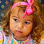 casual, child, closeup, colorful, curly_hair, cute, expression, face, headband, indoor, messy_face, patterned_background, person, pink_bow, portrait, sitting, soft_lighting, striped_clothing, toddler, young_child