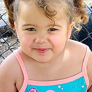 Novalynn is registered to the contest to win money with this photo: child, girl, smiling, curly_hair, pigtails, swimsuit, mermaid, outdoor, fence, portrait, happy, cute, summer, playful, young, person, face, closeup, sunlight, nature