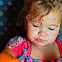 Novalynn is registered to the contest to win money with this photo: child, toddler, curly_hair, colorful_dress, patterned_clothing, face, portrait, indoor, skin, cute, young_child, person, close_up, expression, earrings, sitting, light, warm_tone, background, looking_down
