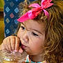 beverage, casual, child, colorful_background, curly_hair, cute, drinking, face, hand, indoor, pink_bow, plastic_cup, portrait, refreshment, sitting, straw, striped_clothing, thoughtful, toddler, young_child