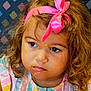 brown_eyes, casual, child, close_up, colorful, curly_hair, cute, expression, face, food_on_face, girl, headband, indoor, patterned_background, pink_bow, portrait, striped_clothing, thoughtful, toddler, young_child