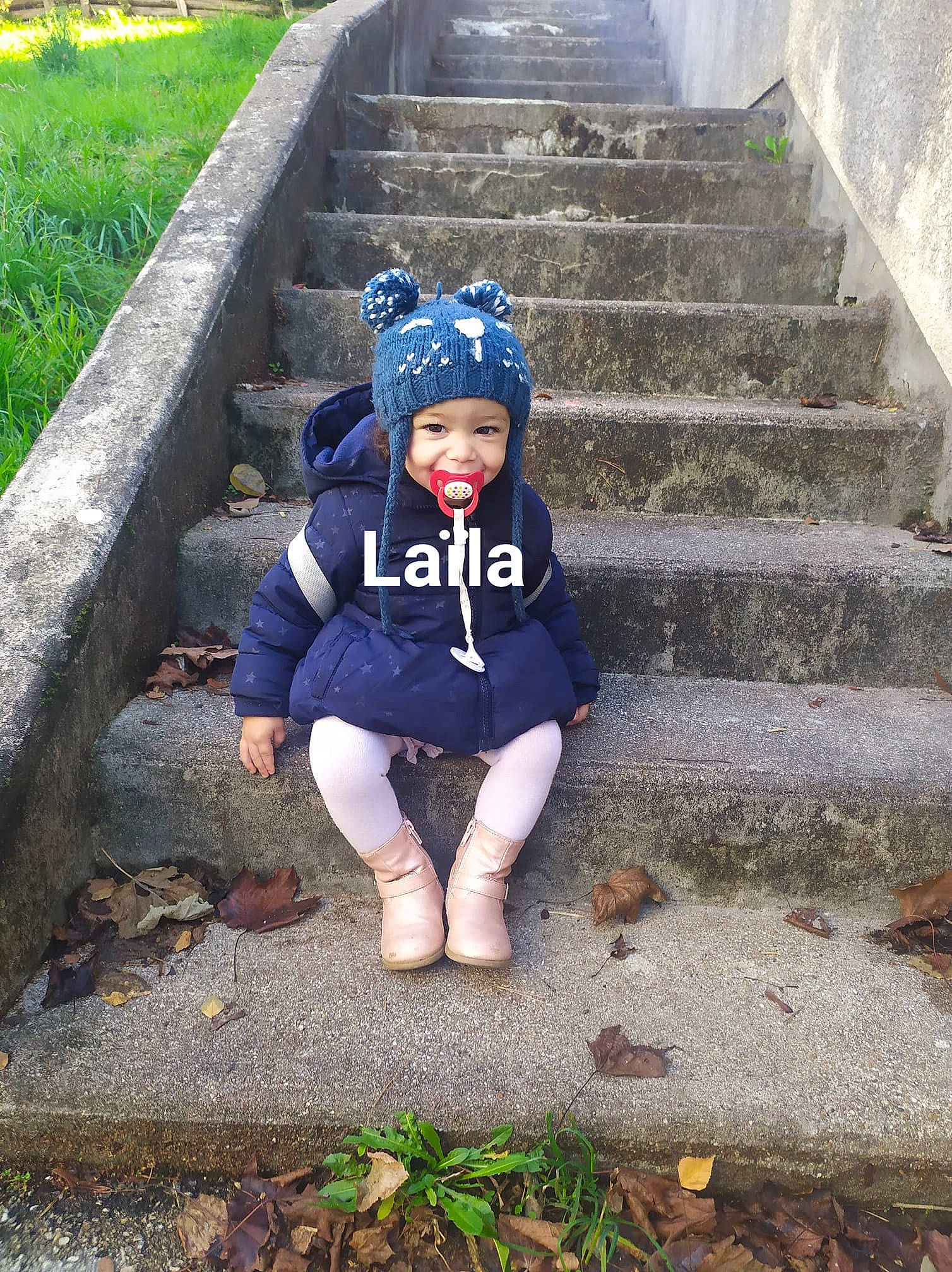 Laïla a rejoint le concours — aidez-le/la à gagner de superbes lots ! beanie, blue, child, grass, headgear, headwear, joy, leaf, leg, outerwear, person, plant, sitting, toddler, tree