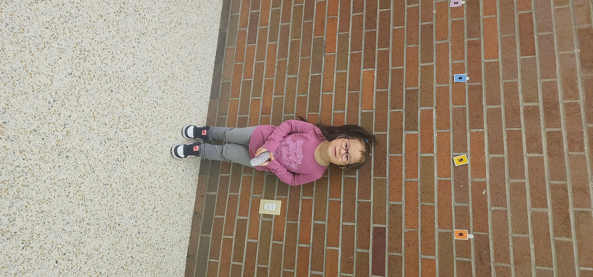 Genesis is registered to the contest to win money with this photo: brick, brickwork, child, concrete, dress, floor, flooring, house, jeans, joy, magenta, pattern, person, pink, plant, purple, road_surface, sidewalk, smile, toddler