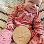 baby, blanket, clothing, cushion, dress, face, furniture, happy, head, homedecor, laughing, newborn, pajamas, person, photography, portrait, quilt, sitting, smile, t_shirt