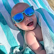 Heath joined the competition — help win amazing prizes! baby, child, towel, sunglasses, smiling, happy, outdoor, beach, sunlight, reflection, skin, head, arm, blanket, summer, cute, portrait, person, relaxing, fun