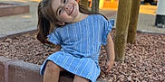 Louana a rejoint le concours — aidez-le/la à gagner de superbes lots ! blue_dress, casual, child, daytime, girl, happy, nature, outdoor, park, playful, portrait, rocks, shoes, sidewalk, sitting, smiling, sunlight, tree, wooden_posts, young_child