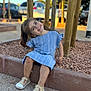 blue_dress, casual, child, daytime, girl, happy, nature, outdoor, park, playful, portrait, rocks, shoes, sidewalk, sitting, smiling, sunlight, tree, wooden_posts, young_child