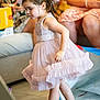 adult, barefoot, candid, celebration, child, curly_hair, cute, dress, family, floor, focused, furniture, girl, home, indoor, movement, party, people, pink, sitting