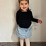Louana participe au concours pour gagner de l'argent avec cette photo : black_shirt, child, cute, denim_skirt, floor, full_body, girl, hair_clip, happy, holding_object, indoor, pigtails, playful, portrait, power_outlet, smiling, standing, wall, white_tights, wooden_floor