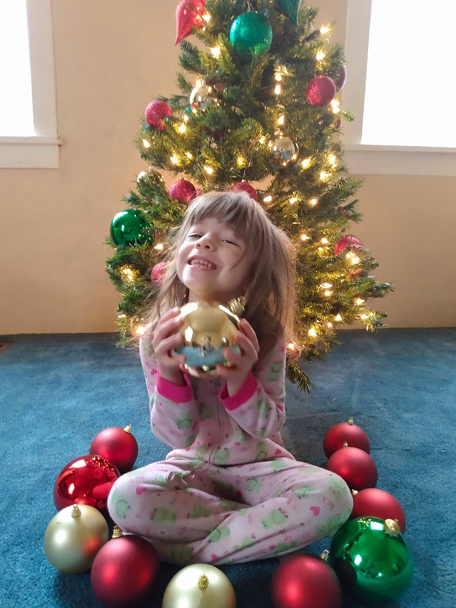 August is registered to the contest to win money with this photo: christmas, christmas_decoration, christmas_eve, christmas_ornament, christmas_tree, event, evergreen, fun, head, holiday, holiday_ornament, human_body, joy, lighting, ornament, party_supply, person, plant, room, smile