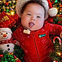 baby, infant, christmas, holiday, santa_hat, red_clothing, tongue_out, plush_snowman, christmas_lights, gift_boxes, festive, smiling, greenery, ornaments, pine_cones, cute, indoors, celebration, portrait, holiday_decor
