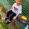 bench, boy, cap, casual, child, daylight, footwear, grass, green, happy, jeans, nature, outdoor, park, person, shoes, sitting, smiling, snacks, tshirt