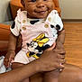 baby, child, infant, smiling, curly_hair, pink_overalls, minnie_mouse, socks, indoor, wood_floor, orange_chair, hand, lap, cute, happy, person, seated, skin, face, portrait