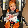 accessories, baby, clothing, coat, costume, face, happy, head, jacket, person, photography, plush, portrait, sitting, smile, stroller, t_shirt, toy, transportation, vehicle
