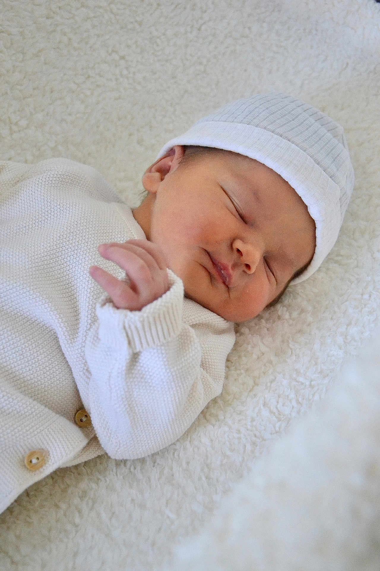 Lilou participe au concours pour gagner de l'argent avec cette photo : baby, newborn, sleeping, white_clothing, hat, blanket, soft_texture, peaceful, infant, cute, portrait, cozy, child, resting, knitwear, hands, face, closeup, indoors, warm