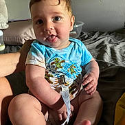 Revan joined the competition — help win amazing prizes! baby, child, infant, toddler, face, tongue_out, blue_clothing, onesie, cute, sitting, bed, hand, foot, skin, room, toy, playful, expression, indoor, person