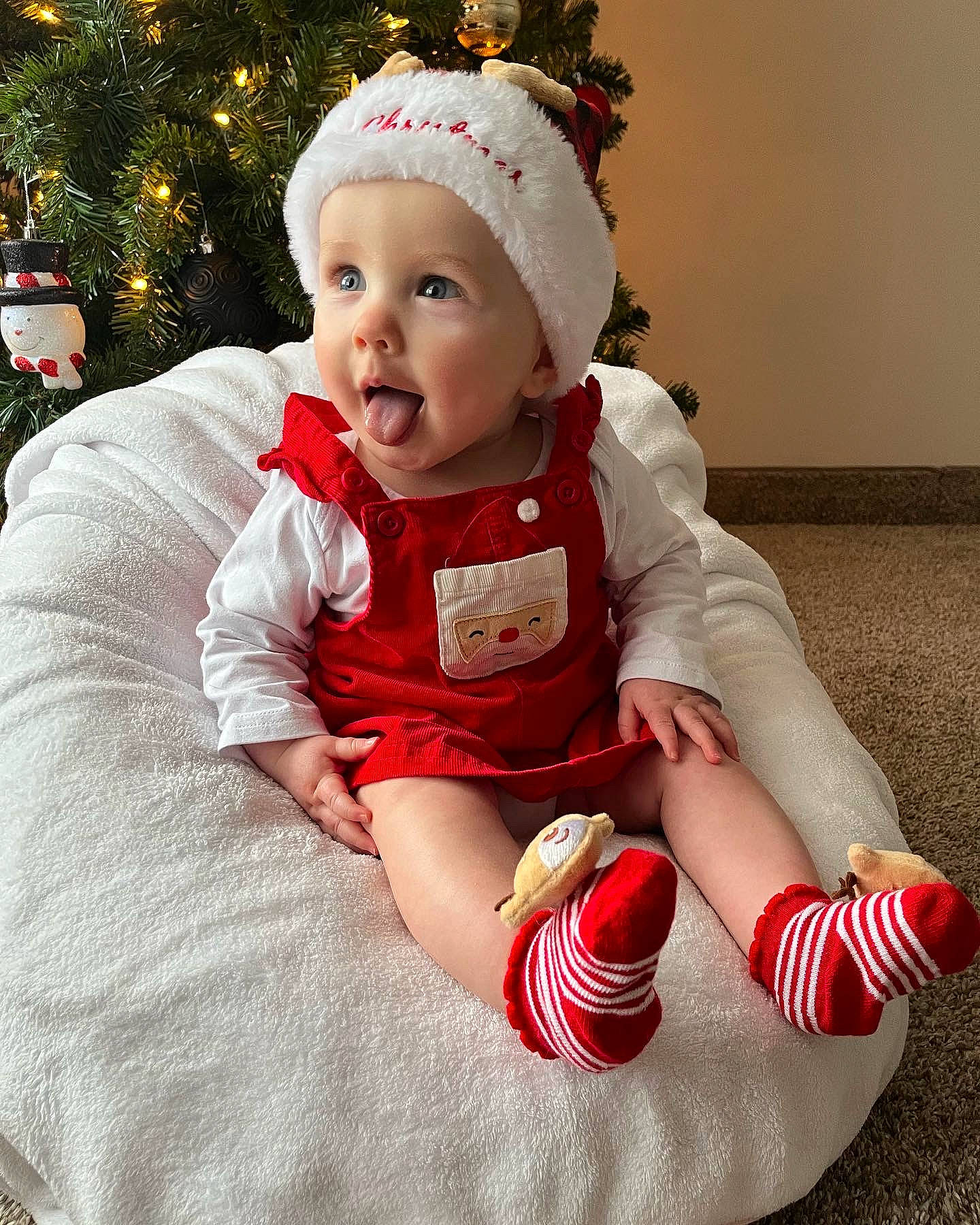 Oaklynn Rae is registered to the contest to win money with this photo: baby, baby_toddler_clothing, christmas, christmas_ornament, christmas_tree, costume_hat, event, foot, happy, hat, headwear, holiday_ornament, human_body, lap, person, pink, red, sleeve, smile, sock
