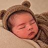 newborn, baby, sleeping, portrait, close_up, face, knit_hat, bear_hat, blanket, swaddled, cozy, indoors, infant, peaceful, closed_eyes, warm_tones, textile, soft_lighting, candid, nursery