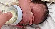 Azraël is registered to the contest to win money with this photo: newborn, baby, infant, feeding, bottle, milk, hand, finger, blanket, bed, bedding, sleeping, lying_down, hair, skin, cozy, indoor, close_up, parenting, portrait